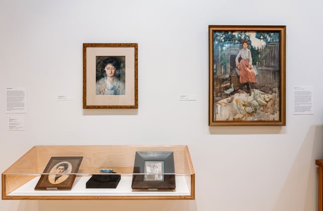 Portraits framed on a white wall inside a gallery.