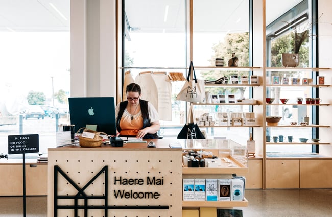 A staff member working behind the counter at Toi Mahara.