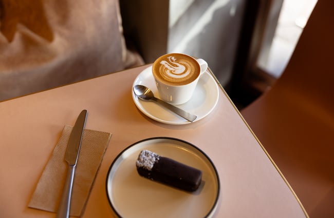 Coffee with swan latte art and chocolate treat on top of cafe table