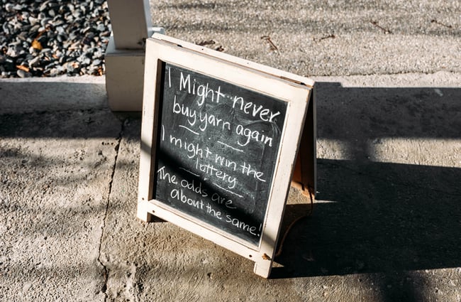 A chalkboard sign on the footpath outside Touch Yarns Clyde Central Otago.