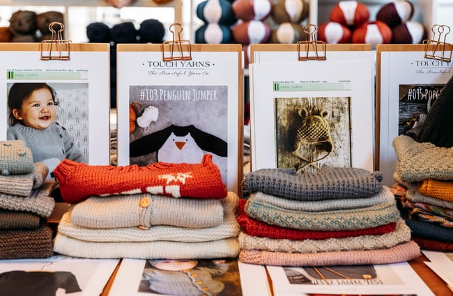 Knitted baby clothes folded and on display.
