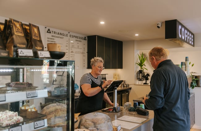 A man ordering from a woman at a cafe counter.