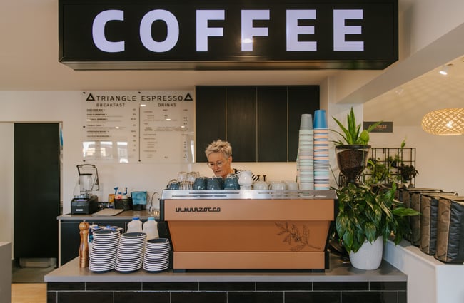 A woman working behind a coffee machine inside a cafe.