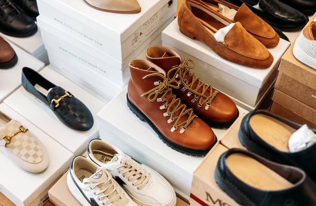 A close up of shoes and boots on display inside a retail store.