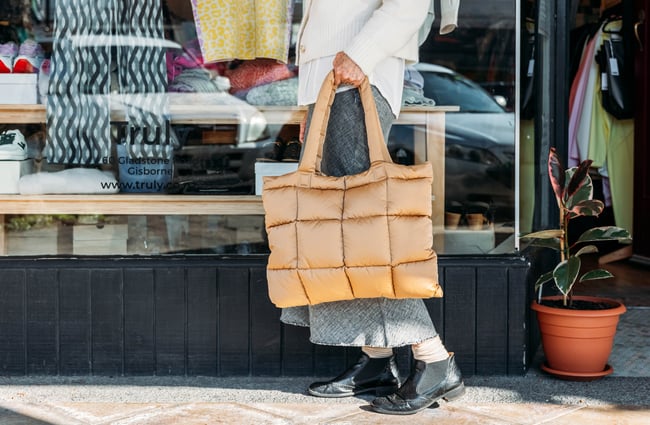 A hand holding a large puffer bag.