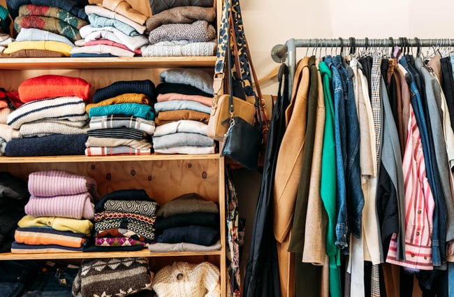 Colourful clothes on display on shelves and a clothing rack.