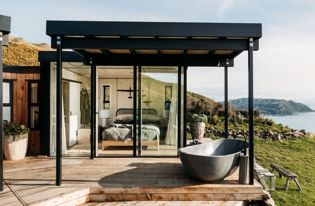 A black and glass B&B on top a hill with the ocean in the background.