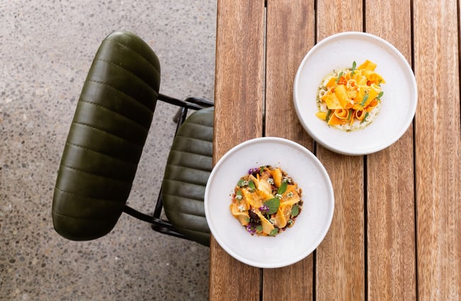 Birds eye photo of a green leather chair beside a wooden table with two dishes on it at Tussock Hill in Christchurch.