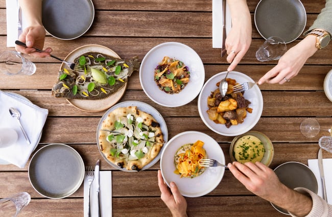 Birds eye view of a table of dishes and three people serving themselves at Tussock Hill Vineyard, Christchurch.