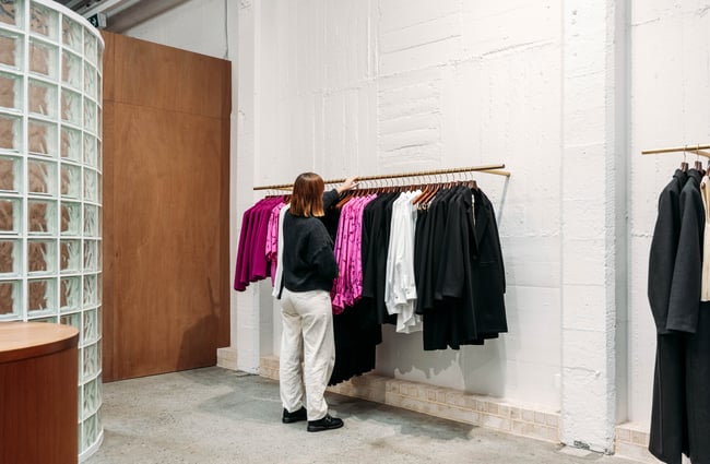 Shop assistant hanging up clothing at twenty-seven names.