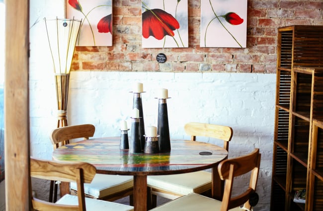Colourful wooden table inside by brick window.