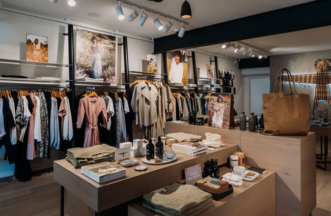 Clothing along the wall and homewares and books on display on a table at Untouched World, Wānaka.