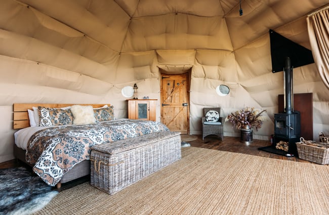 A bedroom set inside a Glamping pod with a wooden panelled floor.