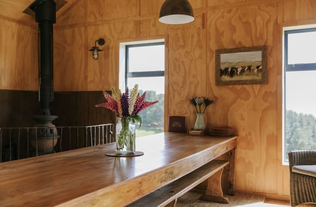 Inside the main hut where there are a vase of flowers on the bench.