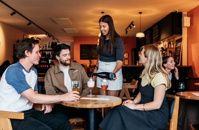 Wait staff pouring a glass of wine for customers at table at Verve.