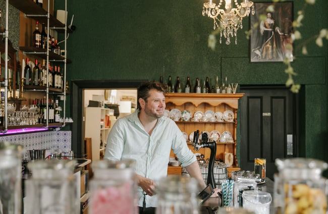A bar man smiling behind the counter at Victoria Lounge.