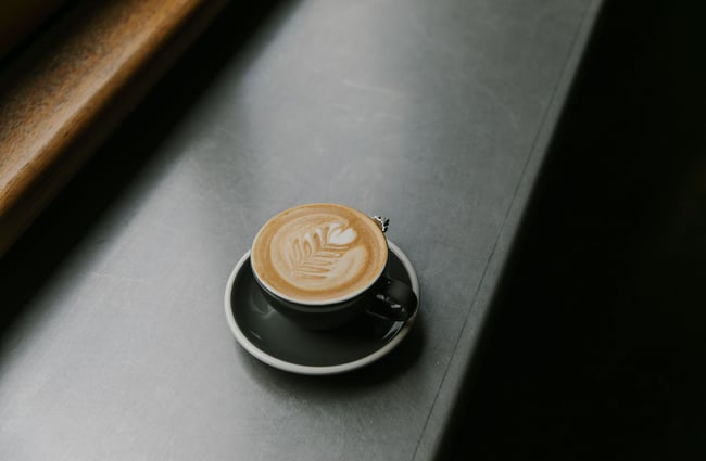 Flat white coffee in a cup on a blue table at Vogel Street Kitchen, Dunedin.