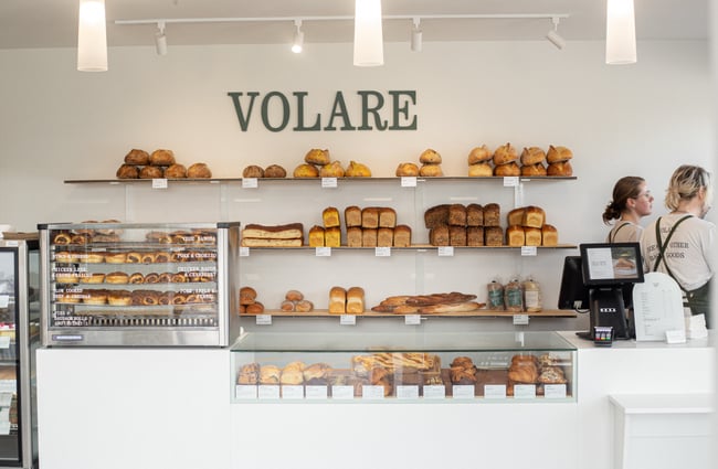 Front counter of Volare Bread with cabinet and shelves filled with bread and pastries.