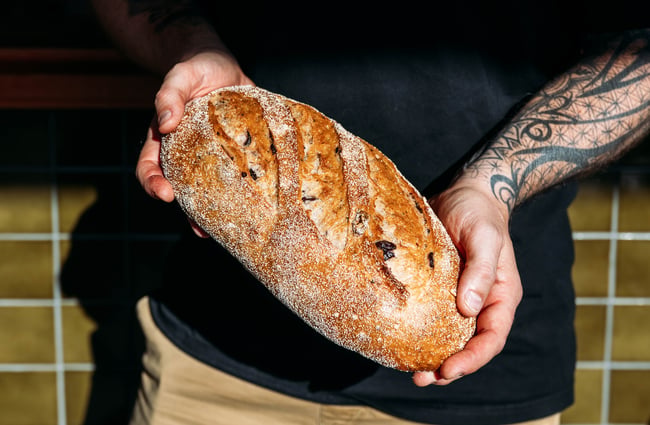 Hands holding a loaf of bread.