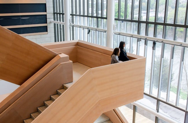 Two women standing on the stairs looking outside at Waikato Regional Theatre.