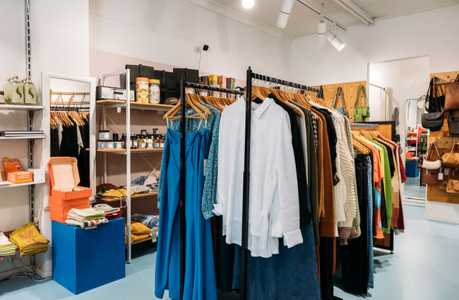 Clothes on racks inside a brightly lit store.