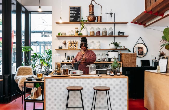 Woman standing behind counter making tea at Wellington Apothecary
