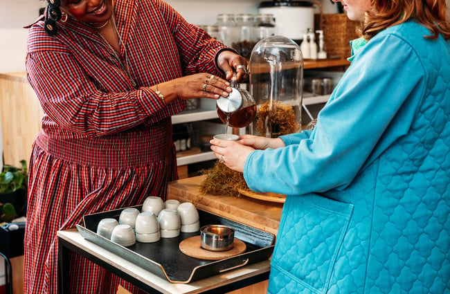 Woman pouring tea for a customer at Wellington Apothecary