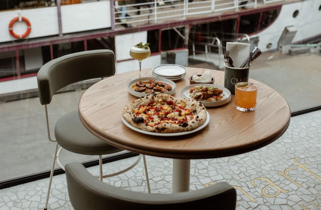 Pizzas, food and cocktails on table at Wharf Bar in Queenstown