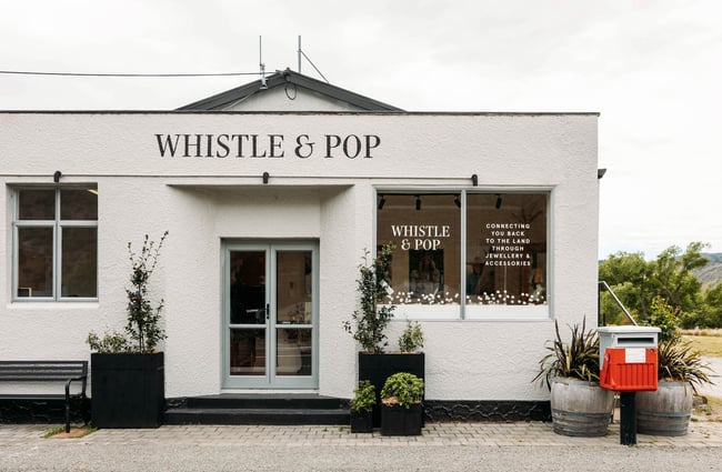White stucco building of Whistle & Pop store with a red postbox outside