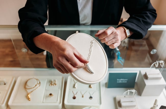 Woman placing hand on silver necklace with a tusk pendant