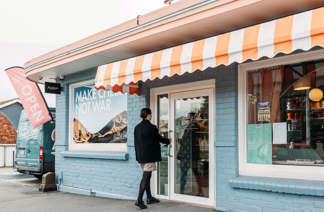 Woman opening door to Whitestone Cheese Deli & Diner