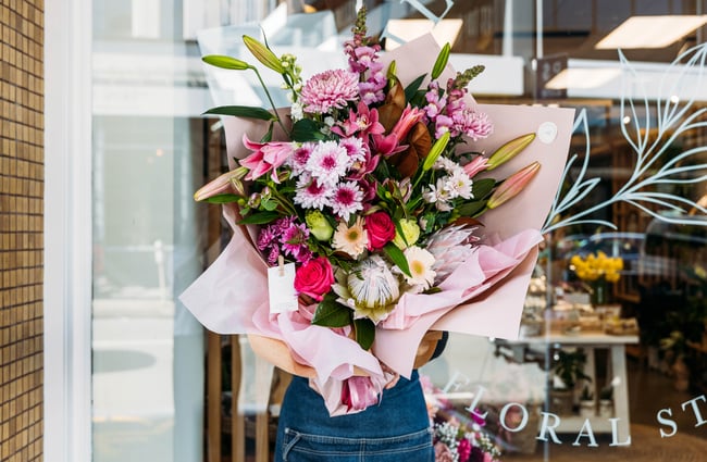 A woman holding a large bouquet of pink flowers.