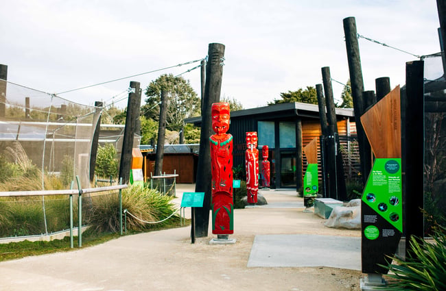 The walkway with big wooden pillars and red statues.