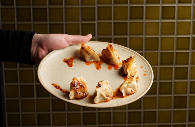 A hand holding a plate of sushi.