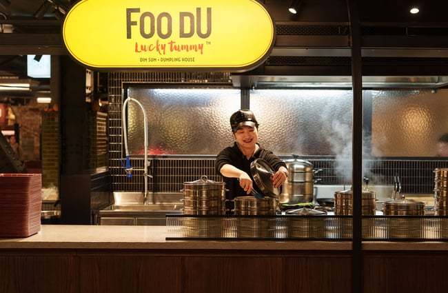 A woman working in an open kitchen smiling.