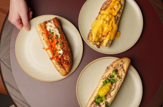 Three delicious looking hot dogs on a table.