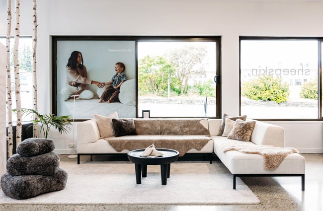 Sheepskin throws and cushions over a large couch and stacked beside it at Wilson & Dorset, Wānaka.