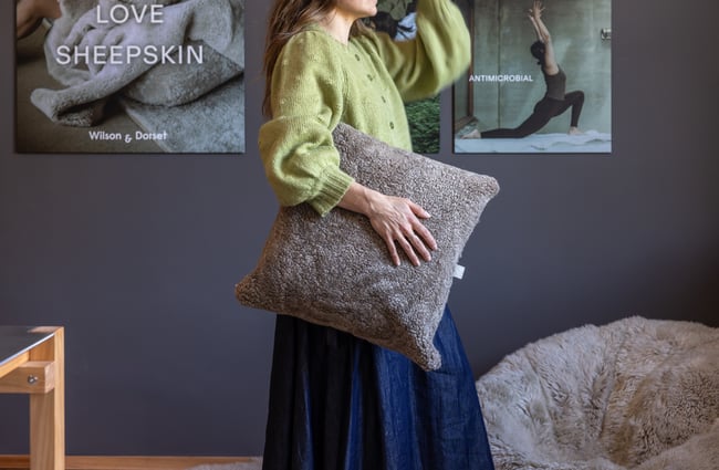 Customer holds sheepskin cushion at Wilson & Dorset.