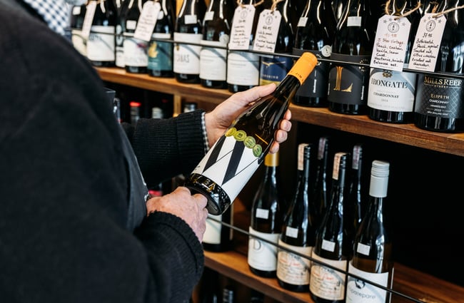 Customer selecting a bottle of wine from the shelf at Wine Craft.