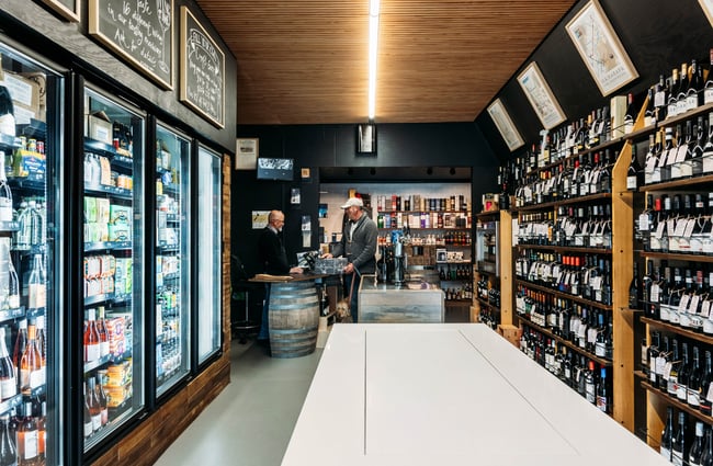 On one side of the shop, there are shelves of wine and the other side has beer fridges at Wine Craft.
