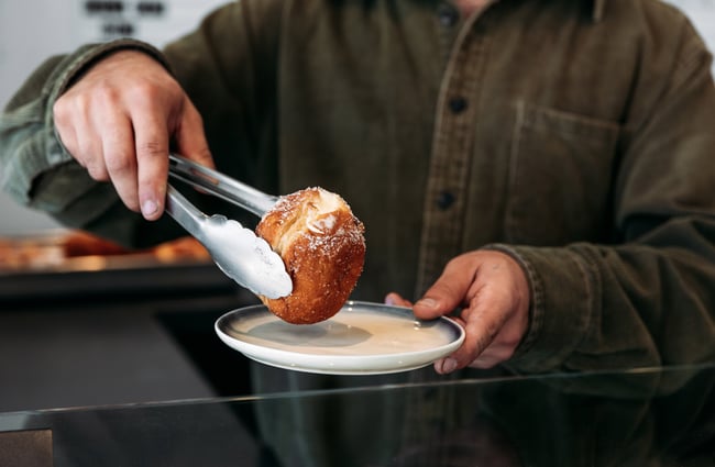 Tongs holding a donut.