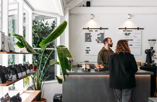 Two people looking in the same direction at a cafe counter.