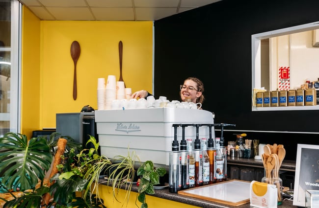 Barista standing behind a coffee machine at Wooden Spoon.