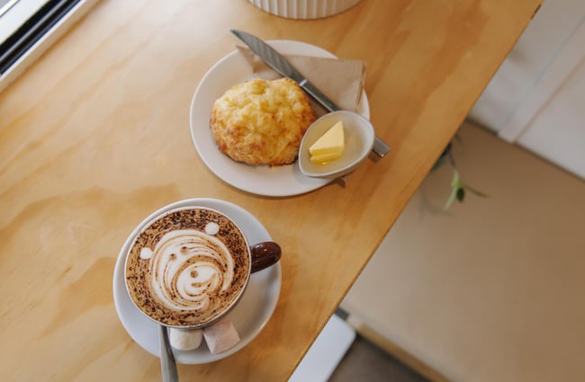 Hot chocolate and cheese scone on a table at Woods Cafe.