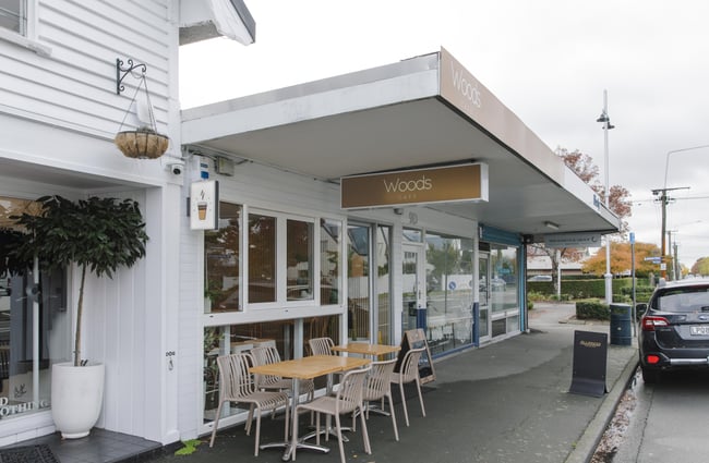 Exterior view of Woods Cafe with tables and chairs outside.