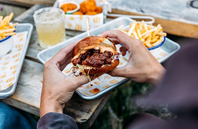 Hands holding a large burger.