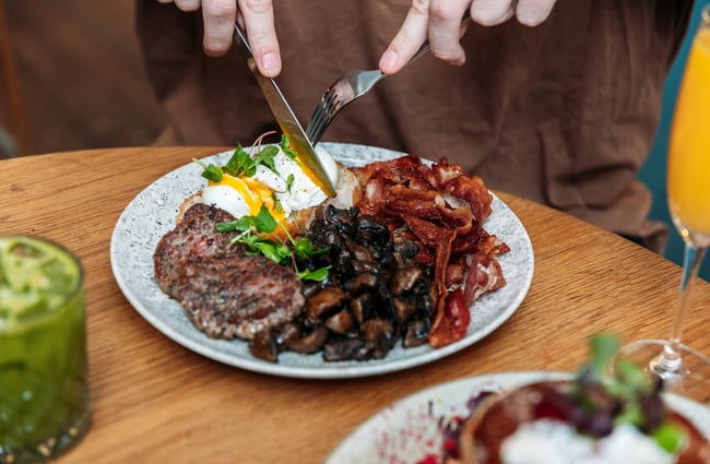 Hands cutting into a plate of food.