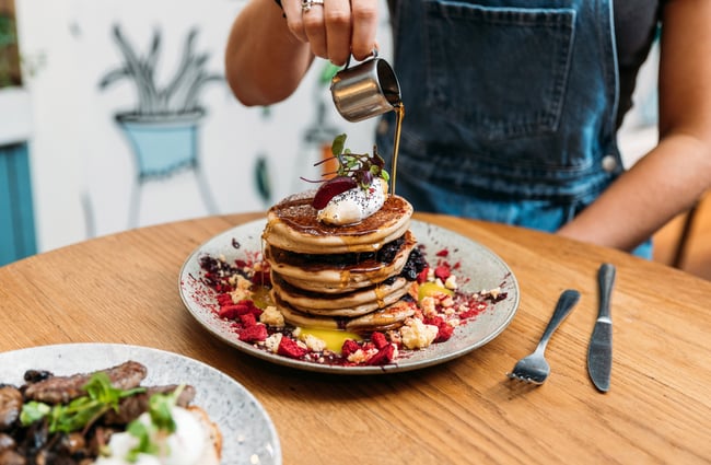 Maple syrup being poured onto pancakes.