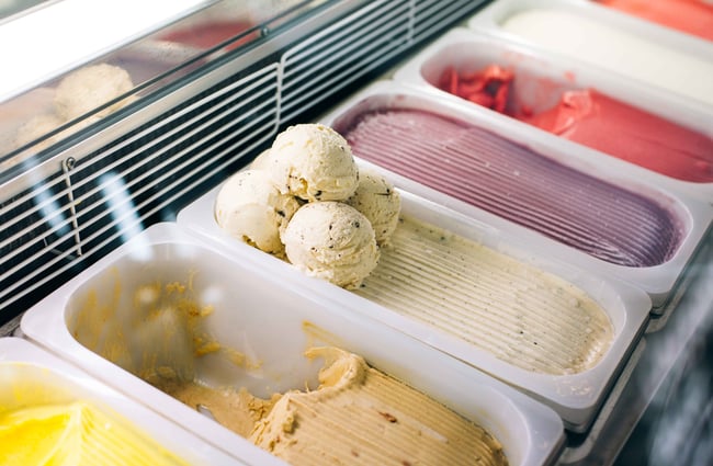 Freezer full of colourful ice cream in tubs.