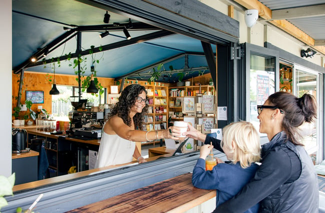 Barista passing a coffee through the window at Hub Matakana.